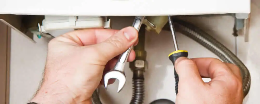 Boiler repair technician tightening pipe fittings and connections in Glendale, AZ