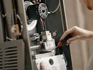 Furnace repair technician inspecting internal components and wiring in Glendale, AZ
