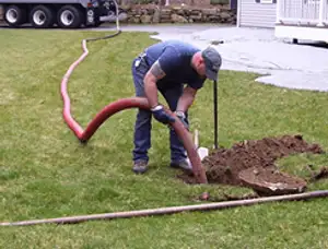 Septic pumping technician servicing a residential septic tank with a vacuum hose in Glendale, AZ