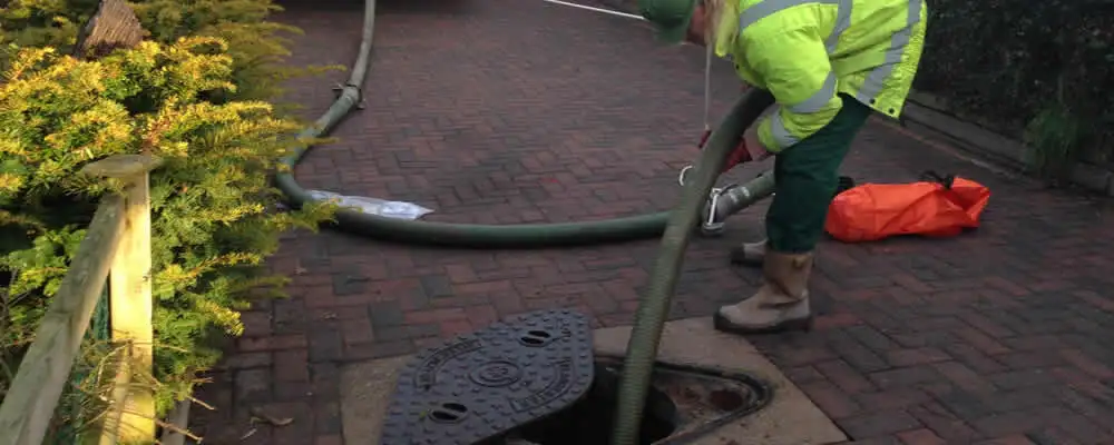 Septic tank cleaning technician servicing a septic tank with a vacuum hose in Glendale, AZ